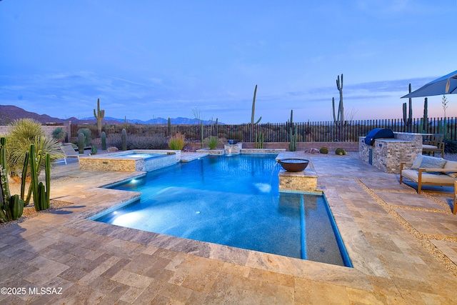 view of swimming pool featuring a pool with connected hot tub, a patio area, a mountain view, exterior kitchen, and a fenced backyard