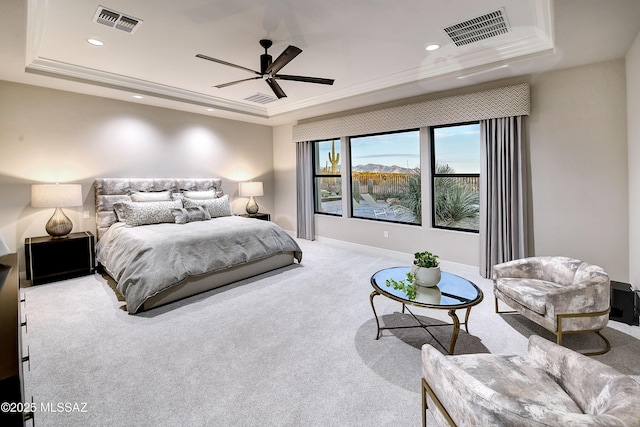 bedroom featuring carpet floors, a tray ceiling, visible vents, and crown molding