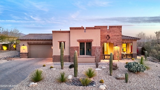 view of front of property with a garage, decorative driveway, a tiled roof, and stucco siding