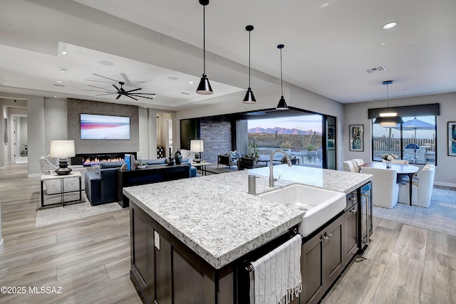 kitchen featuring a kitchen island with sink, light countertops, a sink, and visible vents