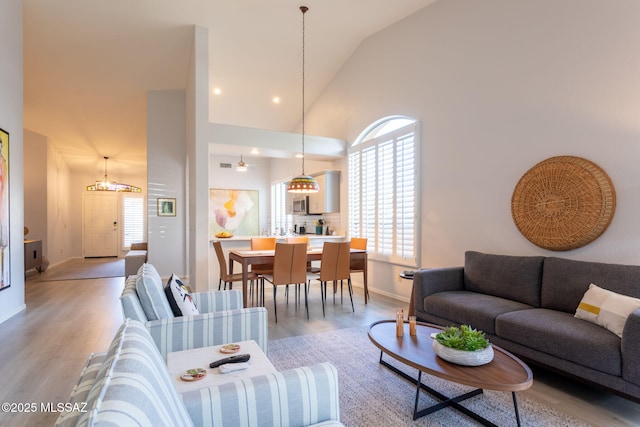 living room featuring light wood-style floors, baseboards, high vaulted ceiling, and recessed lighting