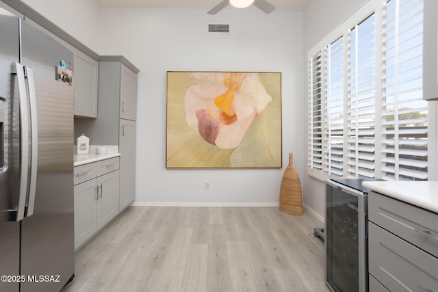 kitchen with wine cooler, gray cabinets, light countertops, light wood-type flooring, and stainless steel refrigerator with ice dispenser