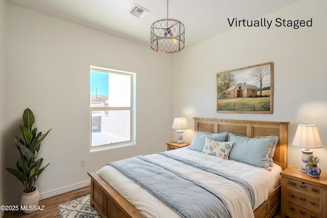 bedroom featuring visible vents, baseboards, and wood finished floors