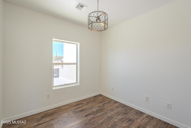 spare room with dark wood-style floors, baseboards, visible vents, and a chandelier