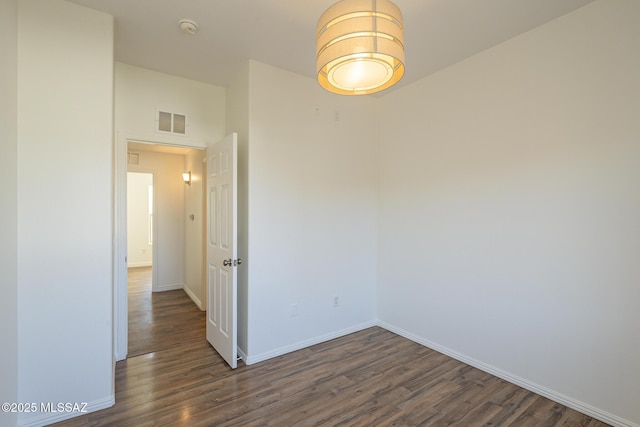 unfurnished room featuring wood finished floors, visible vents, and baseboards