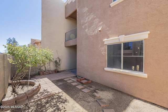 view of side of home with a patio, fence, and stucco siding