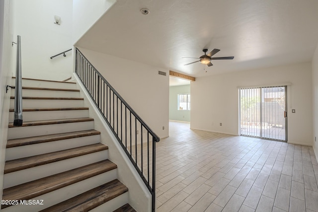 stairway featuring ceiling fan, wood finished floors, visible vents, and baseboards