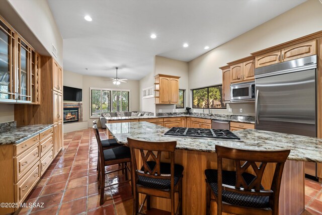 kitchen featuring stainless steel appliances, stone counters, ceiling fan, light tile patterned flooring, and sink