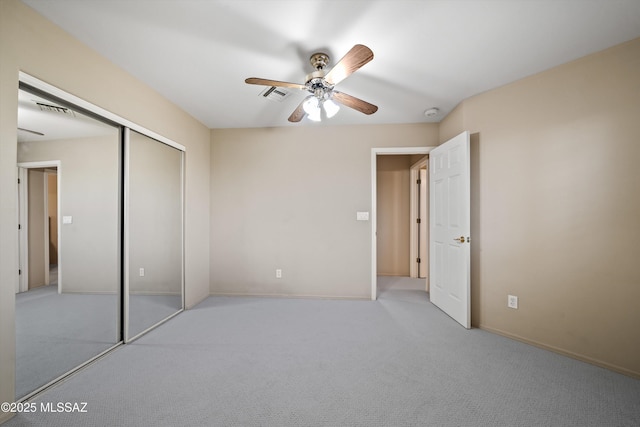 unfurnished bedroom with a closet, light colored carpet, and ceiling fan