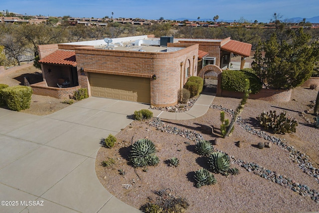 view of front of house with concrete driveway, brick siding, an attached garage, and a gate