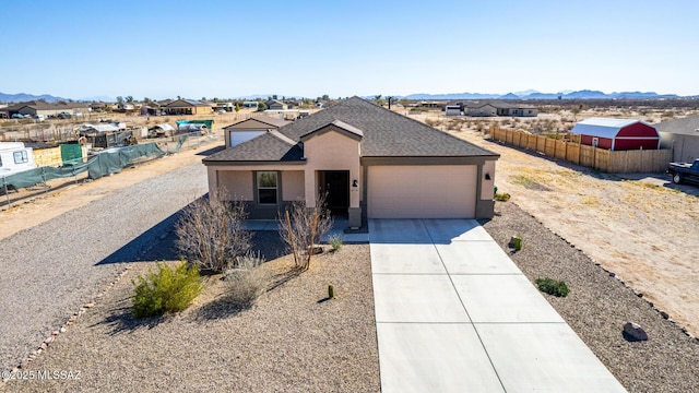 ranch-style home with stucco siding, a mountain view, fence, a garage, and driveway