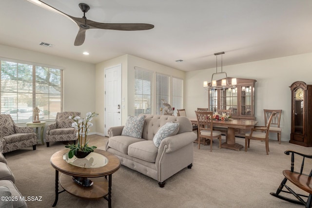 living room featuring ceiling fan with notable chandelier and light carpet