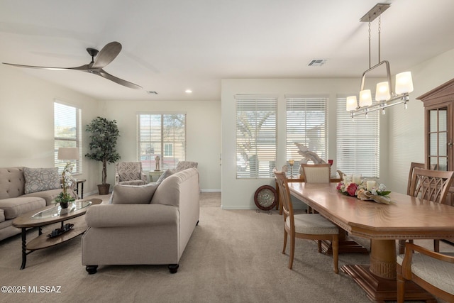 carpeted living room with ceiling fan with notable chandelier
