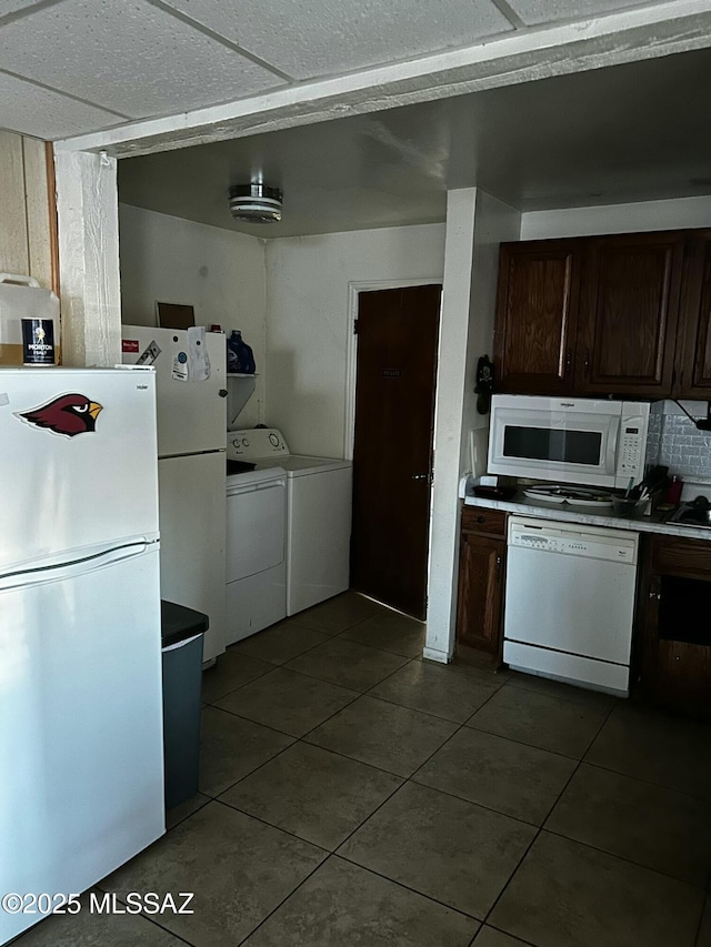 kitchen featuring dark brown cabinets, white appliances, tile patterned flooring, and washer and dryer