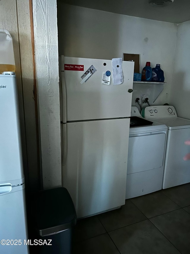 clothes washing area featuring laundry area, dark tile patterned floors, and washing machine and dryer