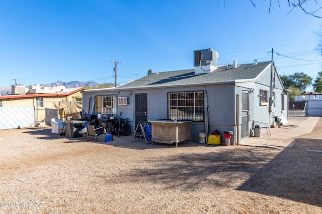 rear view of house with roof with shingles, fence, central AC, and a wall mounted AC