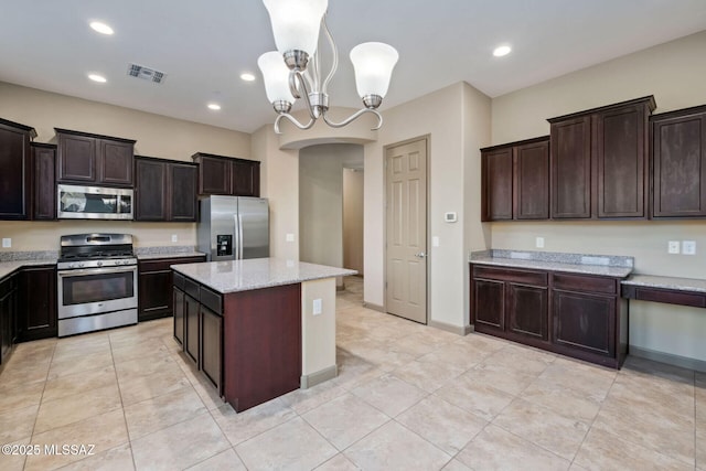 kitchen featuring visible vents, dark brown cabinets, decorative light fixtures, appliances with stainless steel finishes, and arched walkways