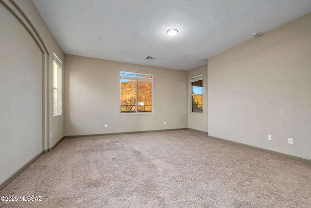 carpeted spare room with baseboards and visible vents