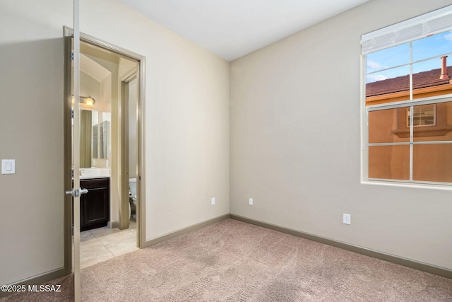 spare room featuring baseboards and light colored carpet