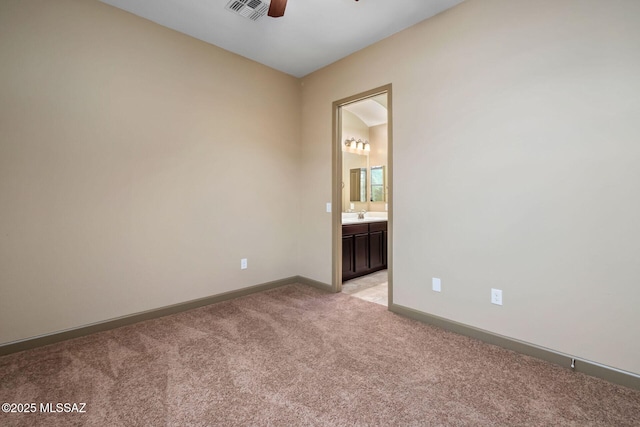 empty room featuring baseboards, visible vents, ceiling fan, a sink, and light carpet