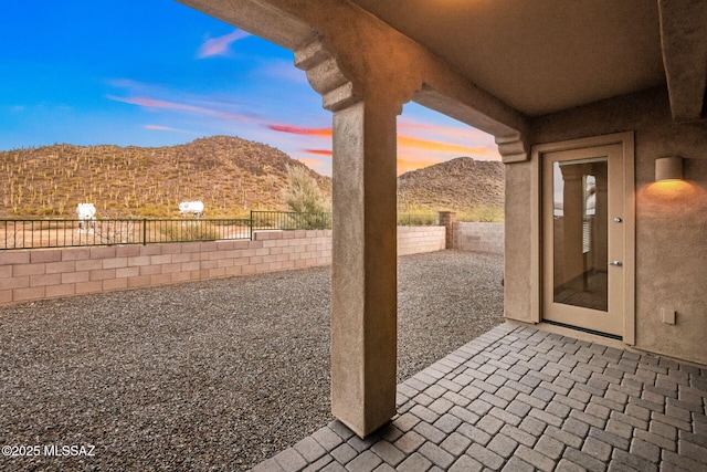 patio terrace at dusk with a mountain view and a fenced backyard