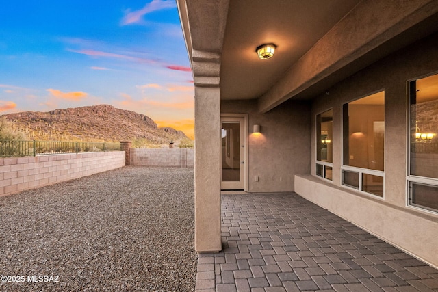 patio terrace at dusk with a mountain view and a fenced backyard