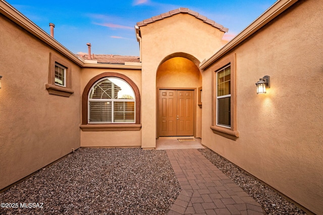 entrance to property featuring stucco siding and a tile roof