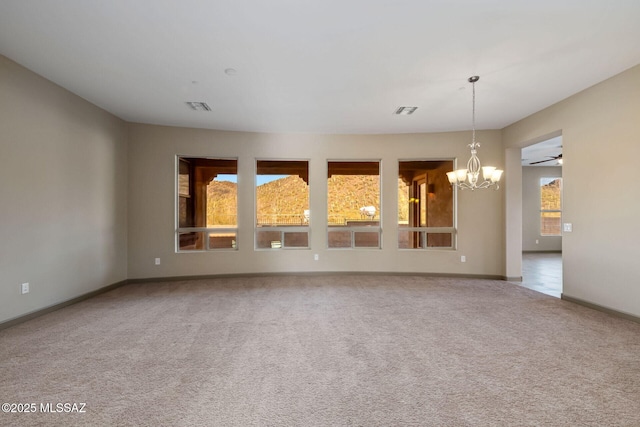 carpeted spare room with visible vents, baseboards, and ceiling fan with notable chandelier