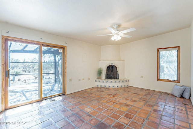 unfurnished living room with a fireplace, visible vents, and ceiling fan