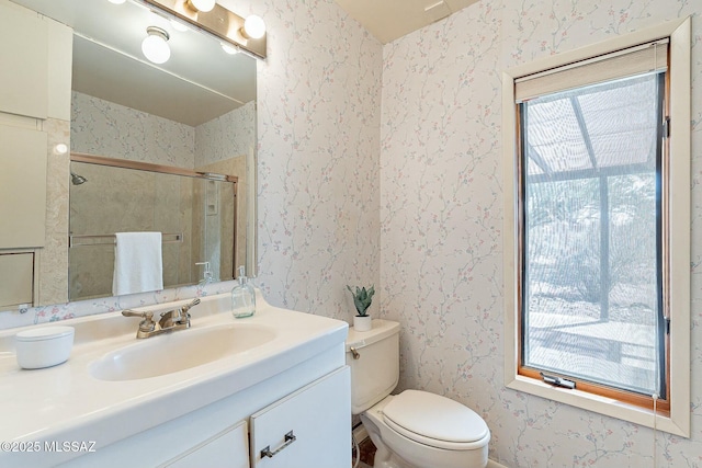 bathroom with toilet, a stall shower, vanity, and wallpapered walls