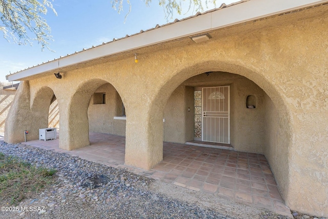 entrance to property featuring a patio area and stucco siding