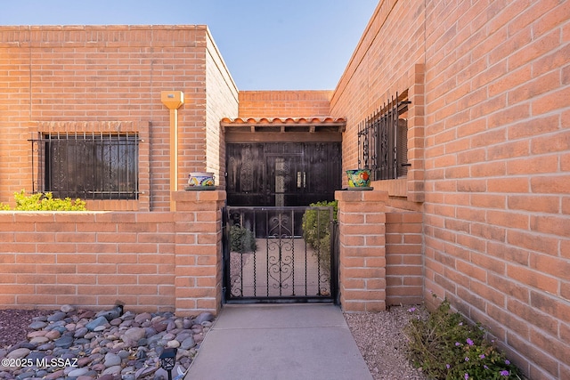 entrance to property featuring a gate and brick siding