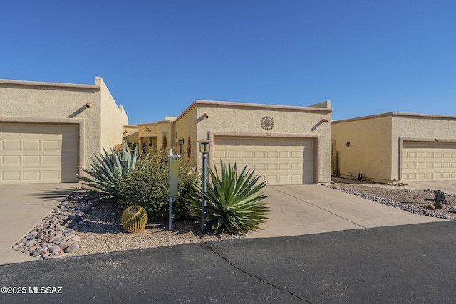 pueblo-style home with concrete driveway and stucco siding