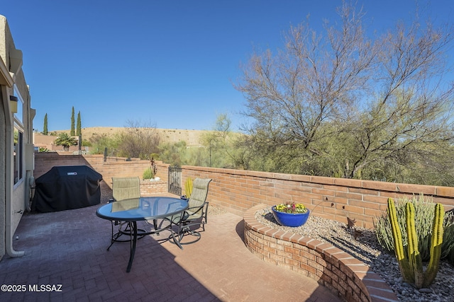 view of patio with a grill, fence, and outdoor dining space