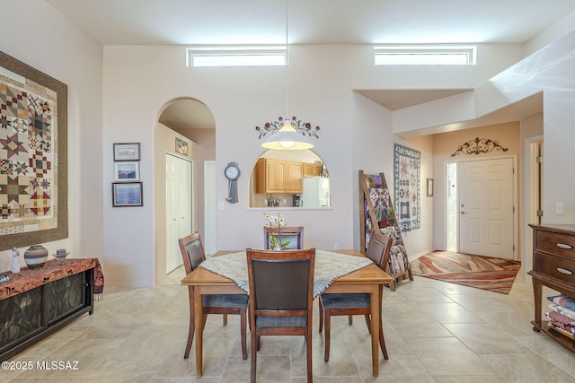 dining space with arched walkways, a high ceiling, and a wealth of natural light