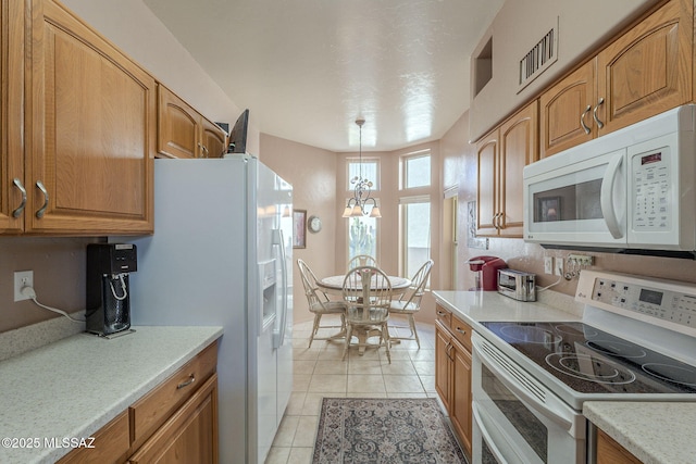 kitchen featuring pendant lighting, light countertops, visible vents, light tile patterned flooring, and white appliances