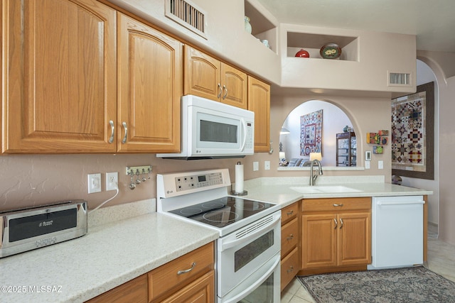 kitchen with light countertops, white appliances, a sink, and visible vents