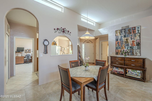 dining room featuring arched walkways, a high ceiling, visible vents, and a healthy amount of sunlight