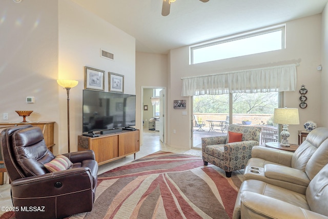 living area featuring light carpet, a high ceiling, visible vents, and a ceiling fan