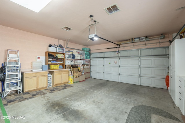 garage with concrete block wall, visible vents, and a garage door opener