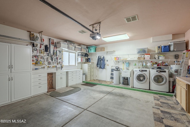 garage with separate washer and dryer, a workshop area, visible vents, and a garage door opener