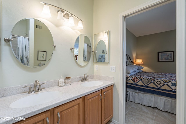 bathroom featuring tile patterned flooring, double vanity, a sink, and ensuite bathroom