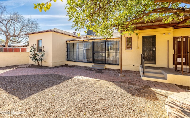 rear view of property featuring a patio, fence, and stucco siding