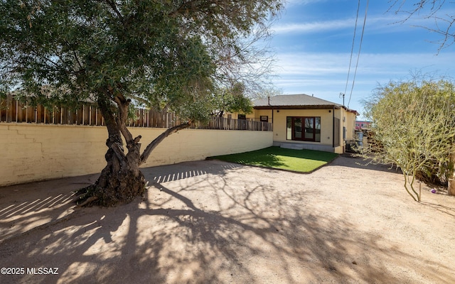 back of property featuring a fenced front yard and stucco siding