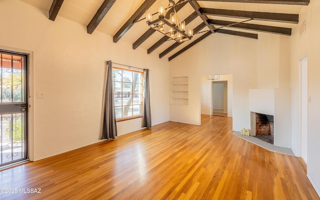 unfurnished living room featuring high vaulted ceiling, beamed ceiling, a fireplace with flush hearth, and light wood-style floors