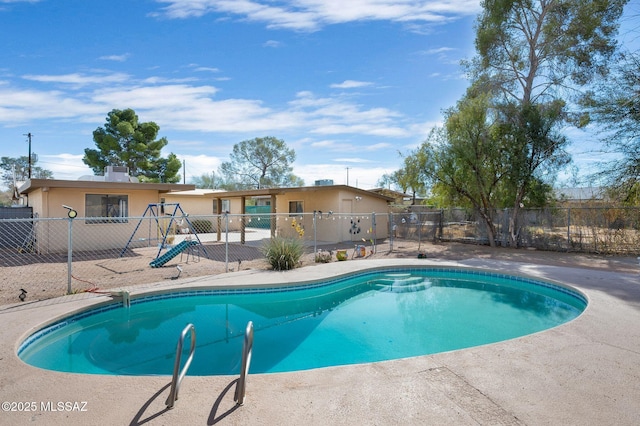 view of pool featuring a playground, fence, and a fenced in pool