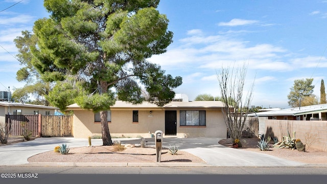 ranch-style home with fence, concrete driveway, and stucco siding