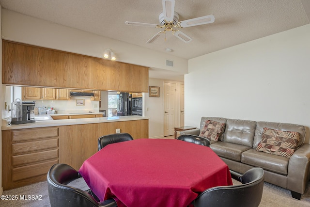 dining area with a ceiling fan, light colored carpet, visible vents, and a textured ceiling