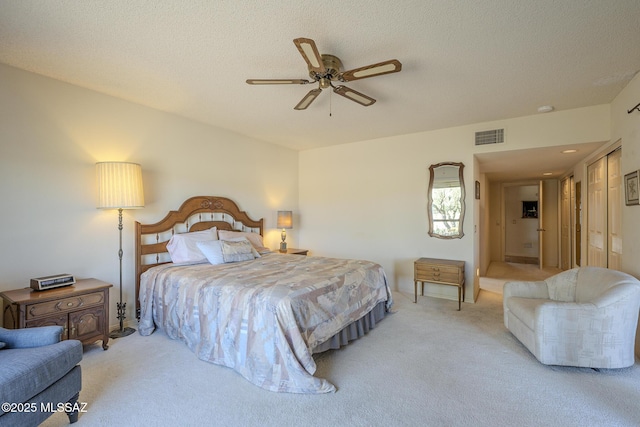 bedroom with light carpet, ceiling fan, visible vents, and a textured ceiling