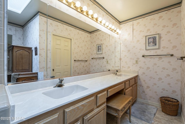 full bathroom with double vanity, a sink, baseboards, and wallpapered walls